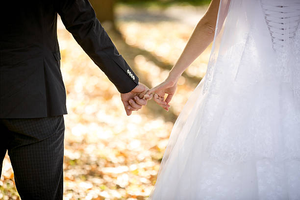 istock young bride and groom holding hands at park 483113094