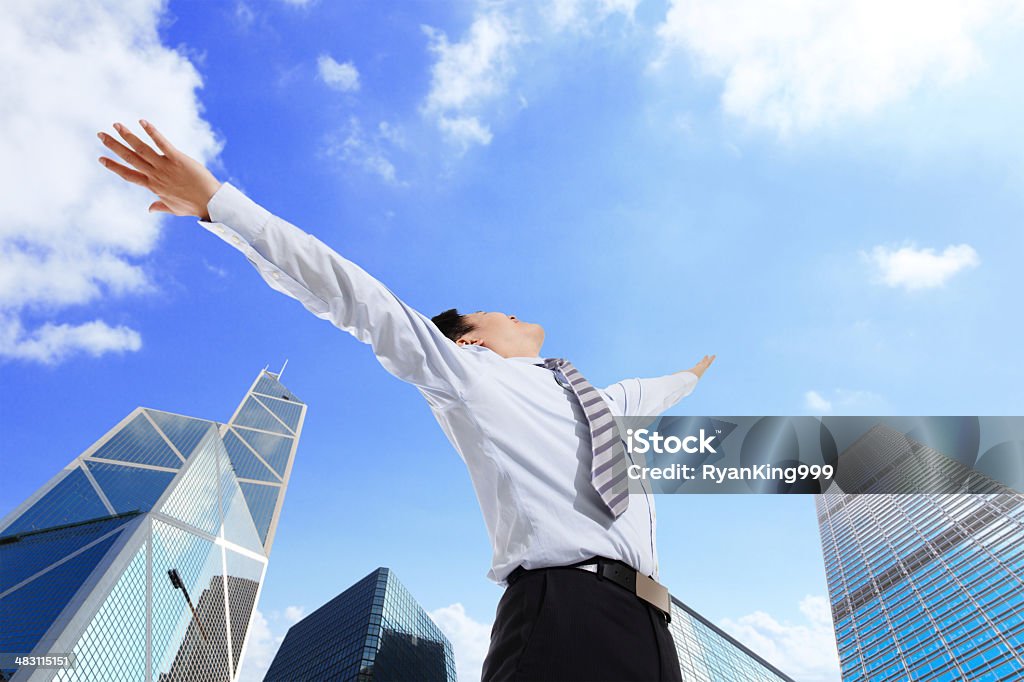 Business man carefree outstretched arms Business man carefree outstretched arms with sky and city background, asian Low Angle View Stock Photo