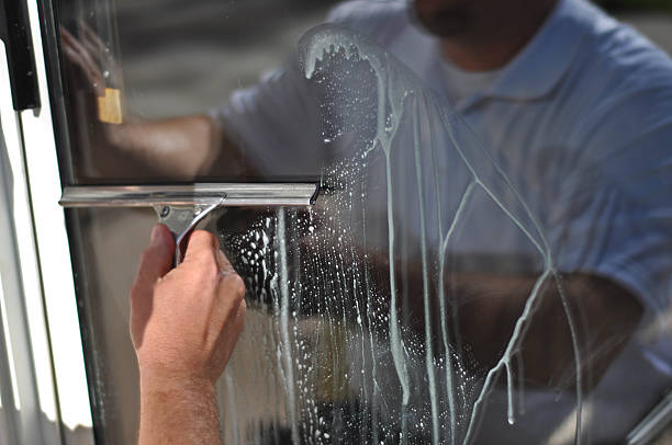 Squeegee Time A window washer uses a small squeegee to clean the exterior glass on a residential sliding door. washing windows stock pictures, royalty-free photos & images