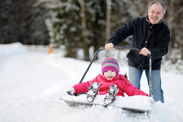 invierno divertido: tener un paseo en pala de nieve - coat grandfather grandchild granddaughter fotografías e imágenes de stock