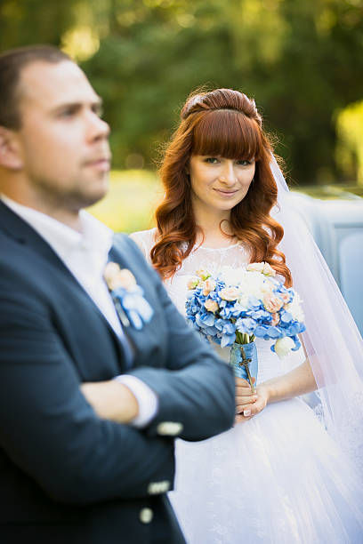 istock cute redhead bride holding bouquet and looking at groom 483116144