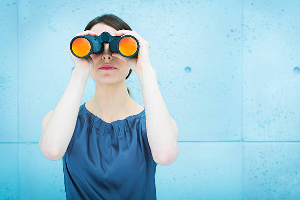 Businesswoman holding binoculars stock photo