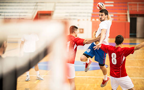 Shooting at goal. Young handball player shooting at goal, while his opponents are trying to stop him.   team handball stock pictures, royalty-free photos & images