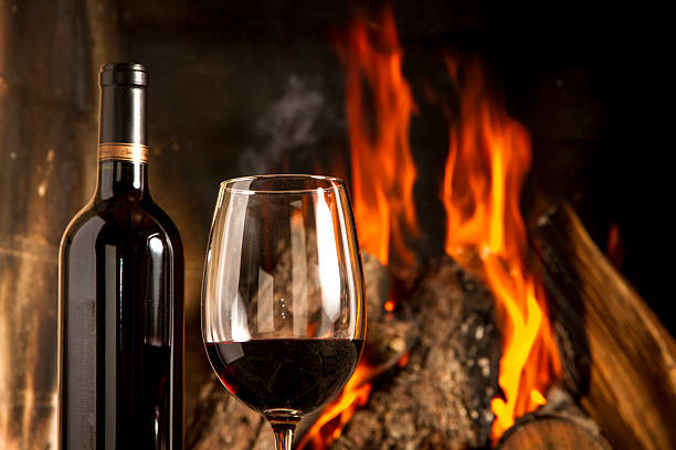 istock Red Wine cup and bottle with fireplace on the background. 483120527