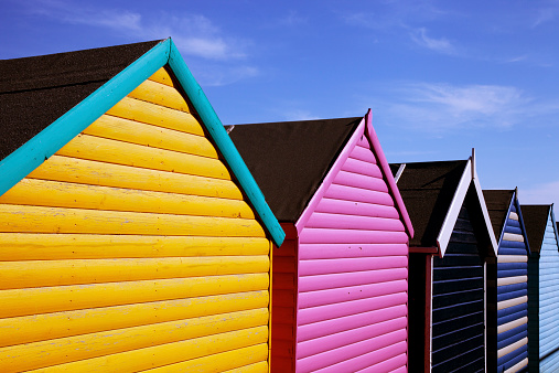 A row of colourful, traditional beach huts at a seaside resort.