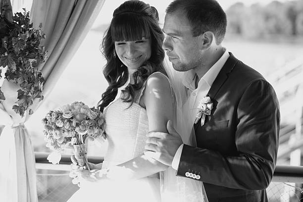 istock Monochrome portrait of groom hugging bride from back 483121582