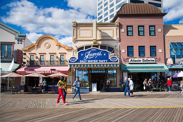 Atlantic City Boardwalk Atlantic City, New Jersey, USA - September 22, 2013:  People walking the Atlantic City Boardwalk in NJ on September 22, 2013. Built in 1870 this historic boardwalk is the oldest in the USA and is now a popular tourist destination lined with restaurants, hotels, casinos and shops.  boardwalk stock pictures, royalty-free photos & images