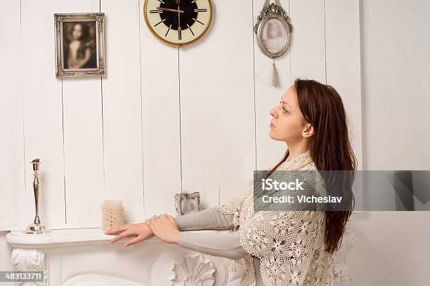 Nostalgic Woman Looking At An Old Family Portrait Stock Photo - Download Image Now - Fireplace, Mantelpiece, Adult