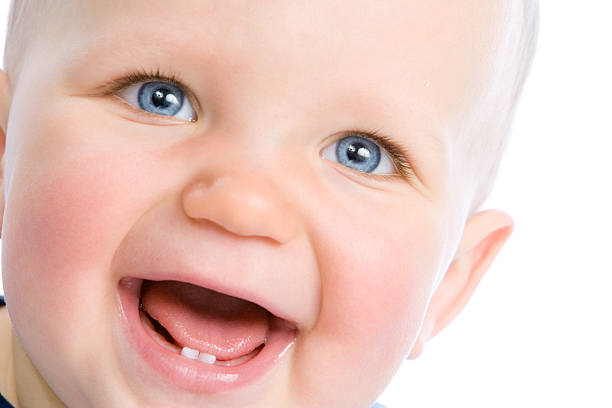 Cute infant laughing Cute baby looking into camera and laughing, showing two teeth baby teeth stock pictures, royalty-free photos & images