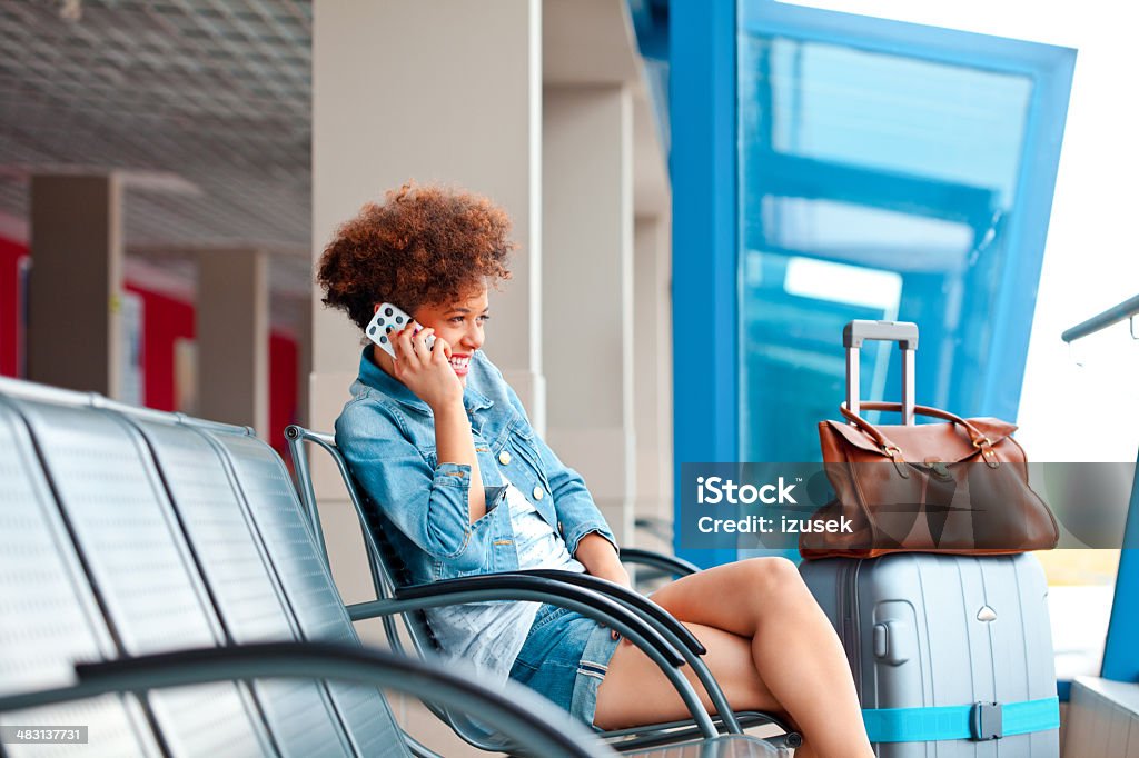 Happy girl on mobile phone A smiling teenaged girl waiting for her flight in a waiting room and talking on the smart phone. Airport Stock Photo