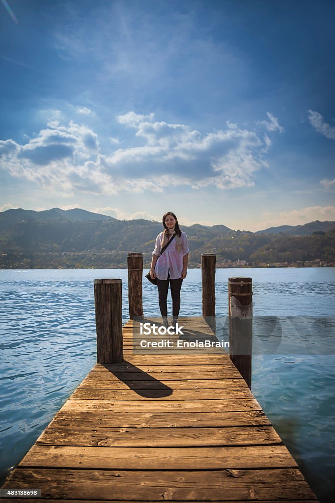 Woman standing on a wooden pier Woman standing on a wooden pier in a blue lake in sunny day 2015 Stock Photo