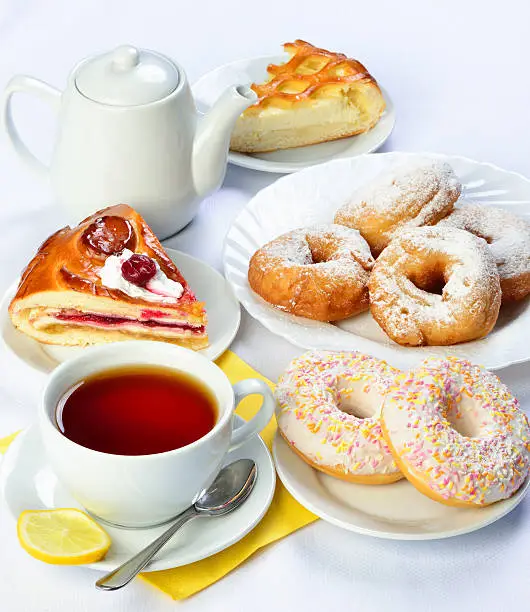 still life of setout table with baking pies, donuts, tee cup and pot. Image with white background. Russian cuisine
