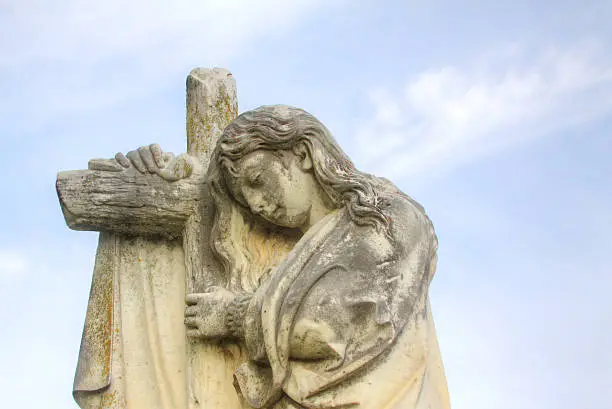 A very old statue in a cemetery is photographed. Copy space provided.
