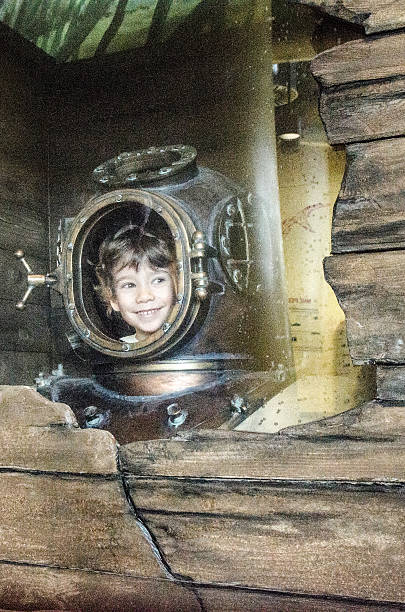 Little boy looking from inside the helmet of an old diving suit. 