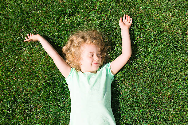 istock Dreaming adorable girl lying on grass, top view 483142398