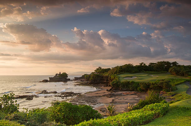 Colorful sunset in Bali on a golf course Sunset on the coastline of Bali, with the holy temple of Tanah Lot. Taken on a golf course, we can see one bunker also. tanah lot sunset stock pictures, royalty-free photos & images