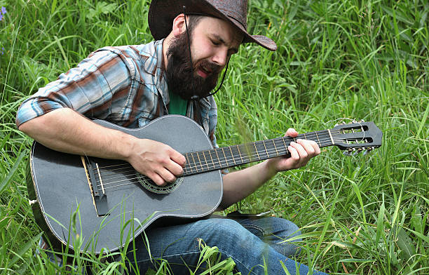 guitarrista en un sombrero de vaquero en la naturaleza - cowboy blue meadow horizontal fotografías e imágenes de stock