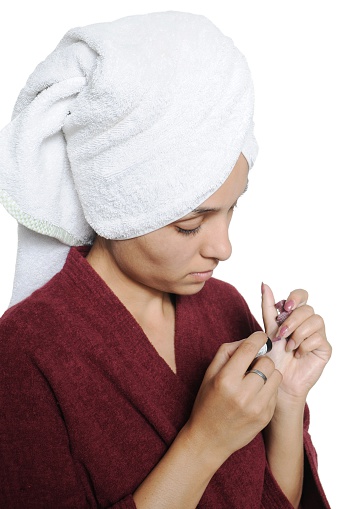 Young lady applying nail color to her finger nails,  after bath.