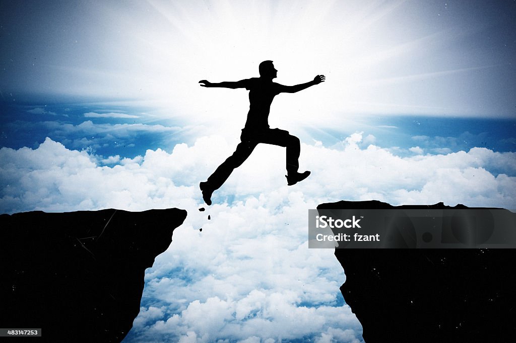 Jumping man silhouette Silhouette of hiking man jumping over the mountains Cliff Stock Photo