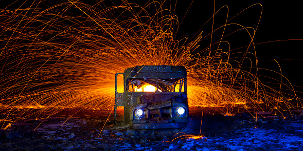 Old Abandoned Bus with Fire and Sparks shooting out from within.  Dark shot at night with spinning steel wool for creating the sparks.