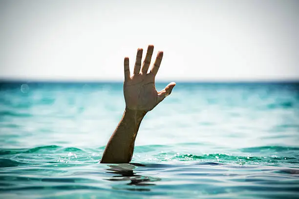Single hand of drowning man in sea asking for help.