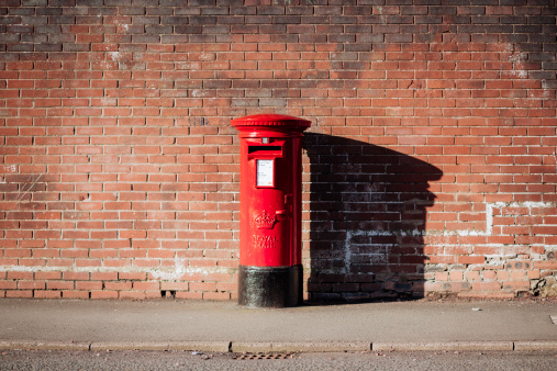 Glasgow, UK - April 6, 2014: A bright red Royal Mail British postbox on the street.
