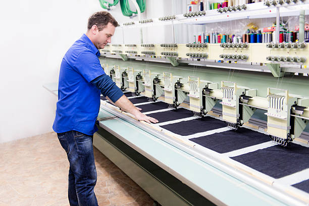istock Male Worker how Set Automatic Embroidery Machine in Textile Factory 483168021