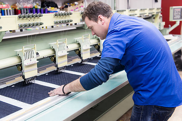 istock Male Worker how Set Automatic Embroidery Machine in Textile Factory 483168141