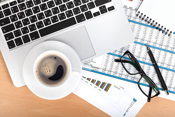 istock Coffee cup, laptop and notepad over papers with numbers and charts 483168469