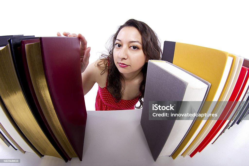Young Female Student Browsing Books on a Bookshelf woman reading books from a bookshelf seen in front view Adult Stock Photo