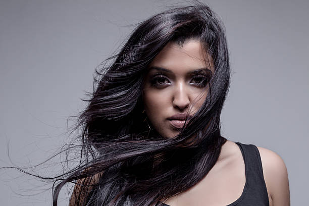 Portrait of a beautiful young woman posing against a grey background