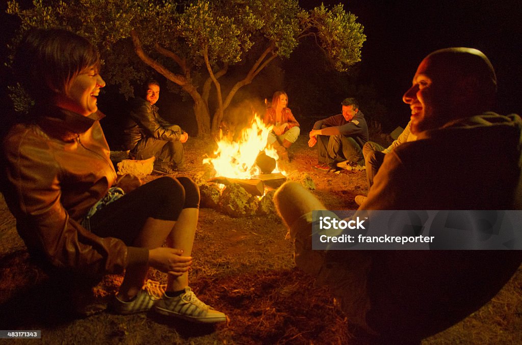 Feu de camp des amis dans le cercle sur le feu - Photo de Feu de camp libre de droits