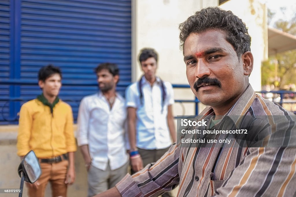 Indian man Kamalapuram, India - February 2, 2015: Indian man on a motorbike next to three young men on a market close to Hampi 2015 Stock Photo