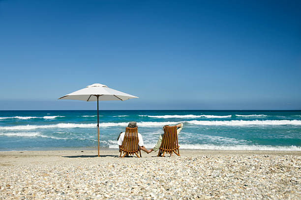 istock retired couple relaxing on beach 483172239