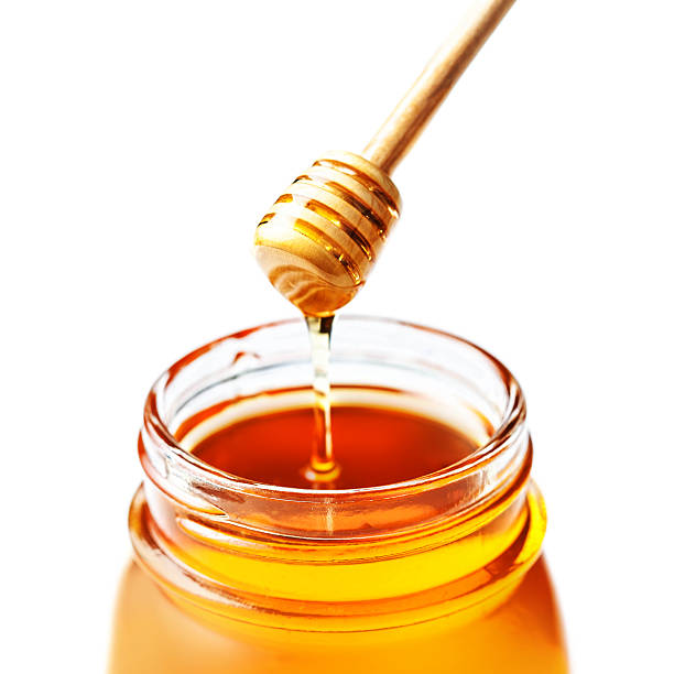istock Honey in a glass jar with dipper  isolated on white 483180526