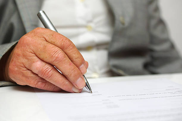 older woman signing the document stock photo