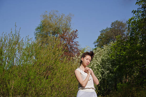 Charming young woman with flowing brunette hair in a bright sunny park, wearing stylish clothing, enjoying the outdoors