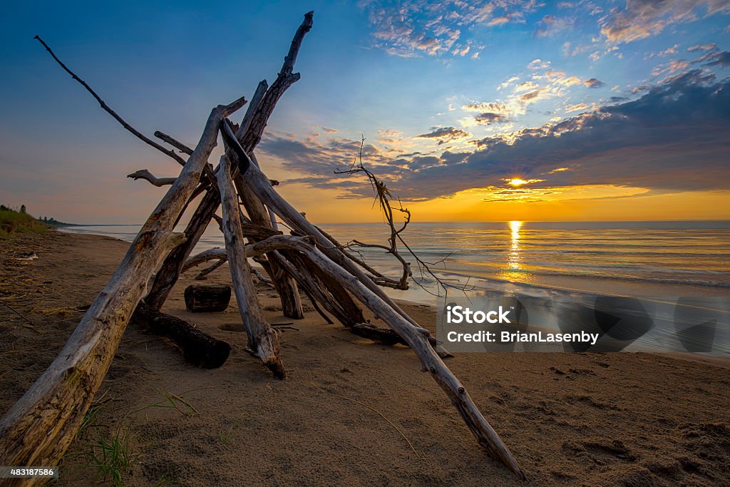 Lean-to on a Lake Huron Beach as the Sun Sets The sun sets behind a leanto built from driftwood on a a sandy beach in Pinery Provincial Park - Ontario, Canada 2015 Stock Photo