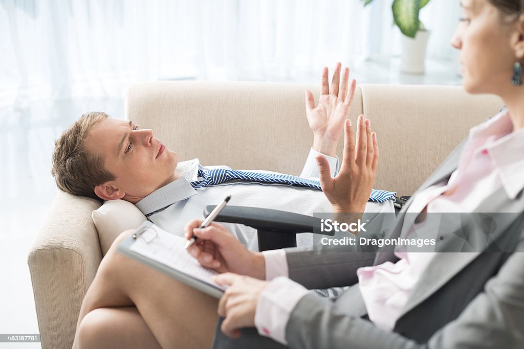 Try to understand me Sad patient trying to explain to his therapist his problems on the foreground Adult Stock Photo