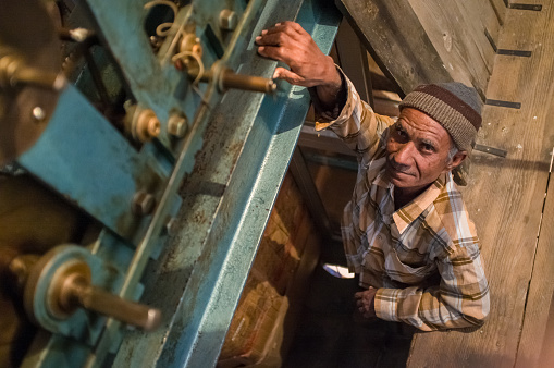 Jodhpur, India - February 11, 2015: Ghanta Ghar clock man stands next to clock mechanism inside tower.