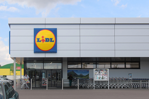 Vienna, Austria - July 11, 2015: Large German grocery store chain Lidl near Designer Outlet Parndorf and people leaving with their shopping bags