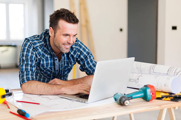 lächeln bauarbeiter arbeiten mit laptop - building contractor computer internet construction worker stock-fotos und bilder