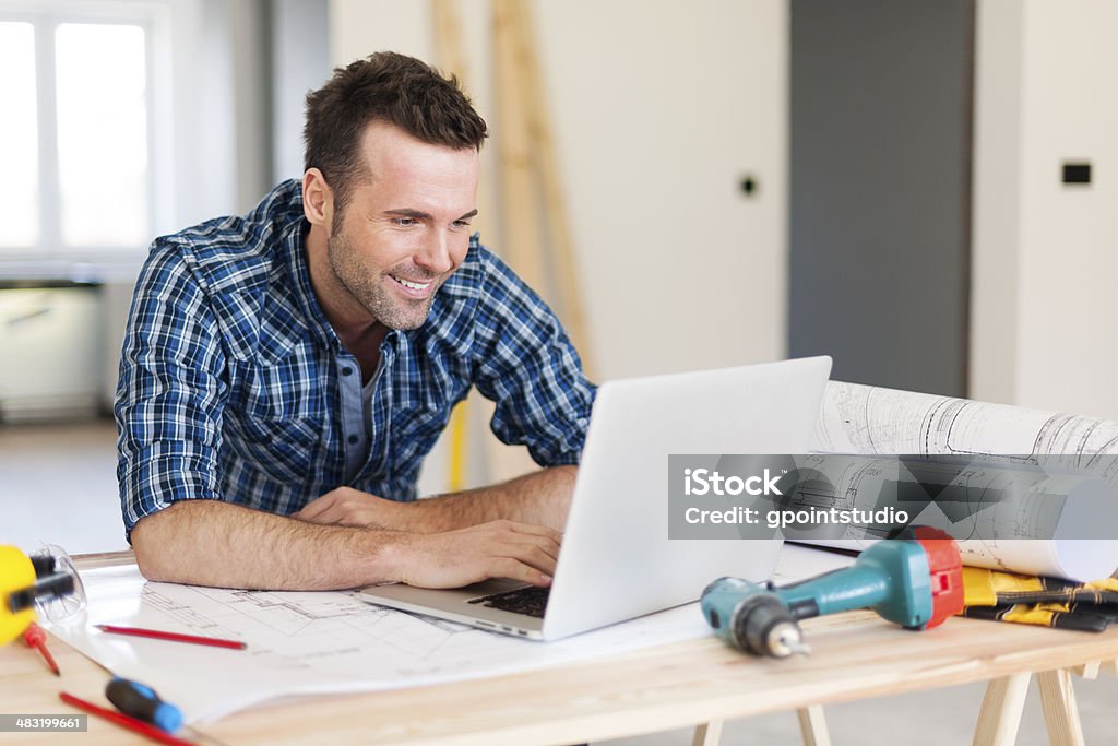 Smiling construction worker working with laptop Smiling construction worker working with laptop  Building Contractor Stock Photo