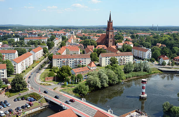 Rathenow, Germany - August 2, 2015: Cityscape of Rathenow with its church from above. (Brandenburg, Germany). Cars on the road driving along over a bridge. In background the centre of Rathenow with stores and market place.