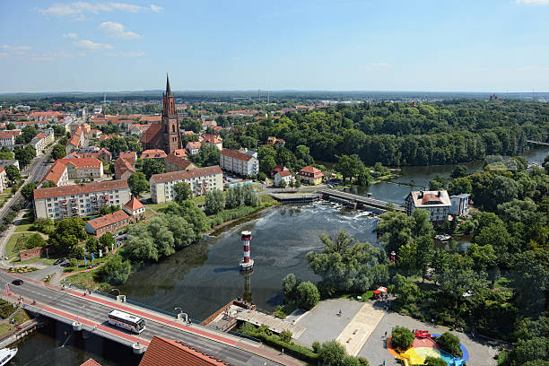 Rathenow, Germany - August 2, 2015: Cityscape of Rathenow with its church from above. (Brandenburg, Germany). Cars on the road driving along over a bridge. In background the centre of Rathenow with stores and market place.