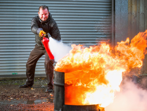 A man using a carbon dioxide extinguisher to fight a fire.