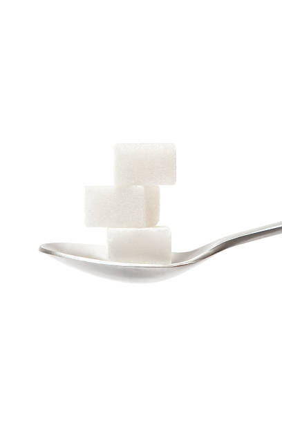 Sugar Cubes on Teaspoon Stack of three sugar cubes on a silver teaspoon. Isolated on a white background. sugar cube stock pictures, royalty-free photos & images