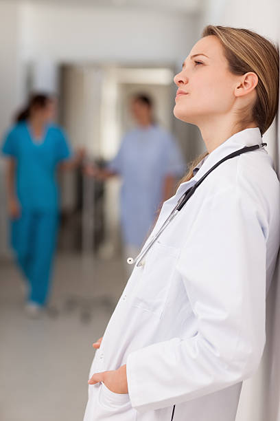 istock Doctor with hands in pockets against a wall 483202091