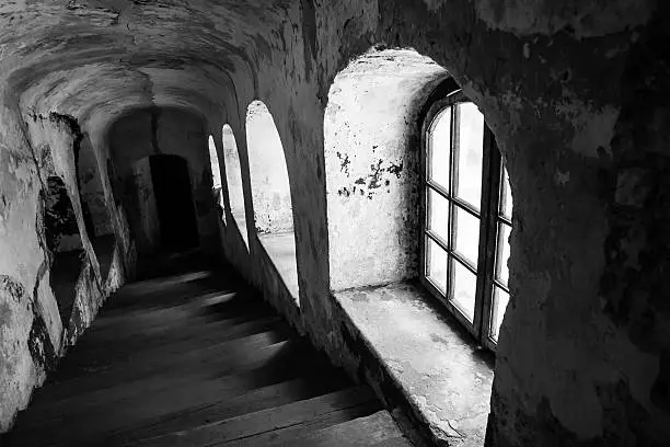 Wooden staris in old building, church with visible windows and damaged walls and plaster, b&w photo.