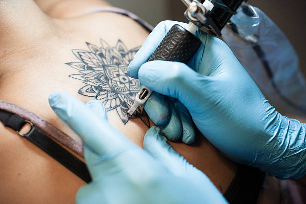 tattoo-künstler bei der arbeit - tätowierung stock-fotos und bilder